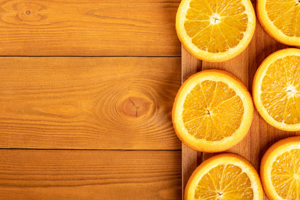 Sliced oranges on board on wooden table. Copy space - Foto, Imagem