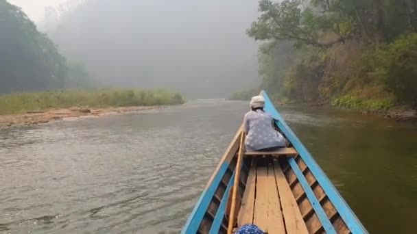 Μικρό ξύλινο σκάφος που πλέει σε ένα άγριο τροπικό ποτάμι στην καταπράσινη ζούγκλα με μια γυναίκα να κάθεται μπροστά στο σκάφος και να κοιτάζει ειρηνικά το τοπίο. Μπλε κανό εξερεύνηση της φύσης. - Πλάνα, βίντεο