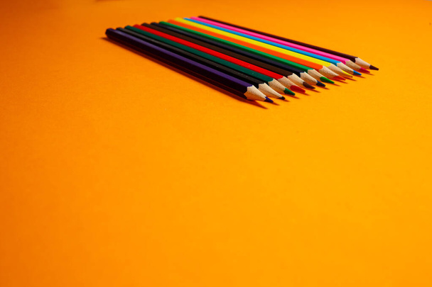 sokszínű ceruzák rajzolásához halmozott narancssárga háttér. Levélpapírtermékek - Fotó, kép