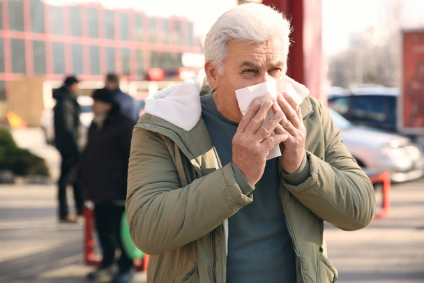 Beteg öregember zsebkendővel a város utcáján. Influenza vírus - Fotó, kép