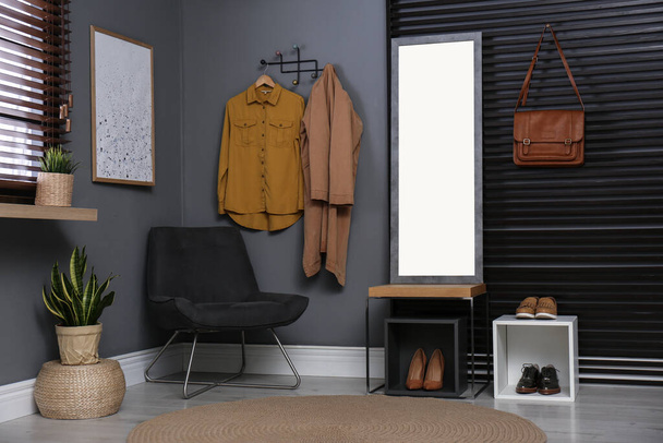 Hallway interior with modern furniture, mirror and hanging clothes - Foto, immagini