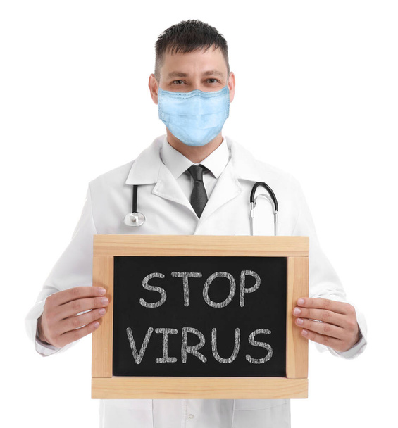 Lekarz w masce medycznej trzymający tablicę z napisem STOP VIRUS na białym tle - Zdjęcie, obraz