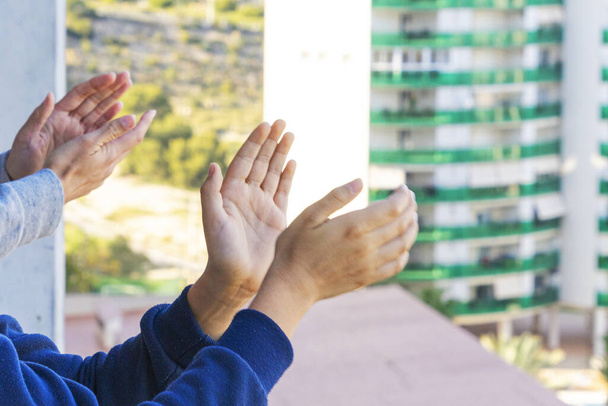 Οικογένεια χειροκροτεί ιατρικό προσωπικό από το μπαλκόνι τους. Άνθρωποι στην Ισπανία χειροκροτούν σε μπαλκόνια και παράθυρα προς υποστήριξη των εργαζομένων στον τομέα της υγείας κατά τη διάρκεια της πανδημίας του Coronavirus - Φωτογραφία, εικόνα