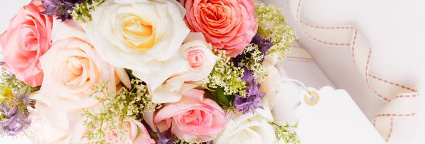 Λεπτό μπουκέτο από ροζ τριαντάφυλλα και δώρα με κορδέλα στο τραπέζι. - Φωτογραφία, εικόνα