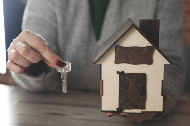 woman hand key with house model on dark background - Valokuva, kuva
