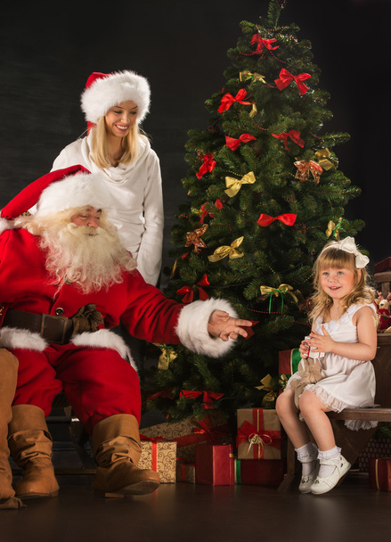 Photo of cute girl and her mother and Santa Claus at home - Фото, изображение