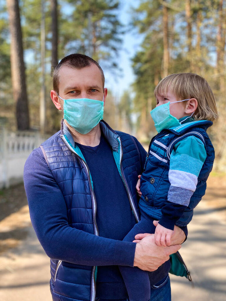 Uomo e bambino dalla pelle chiara in maschere protettive mediche per strada
. - Foto, immagini