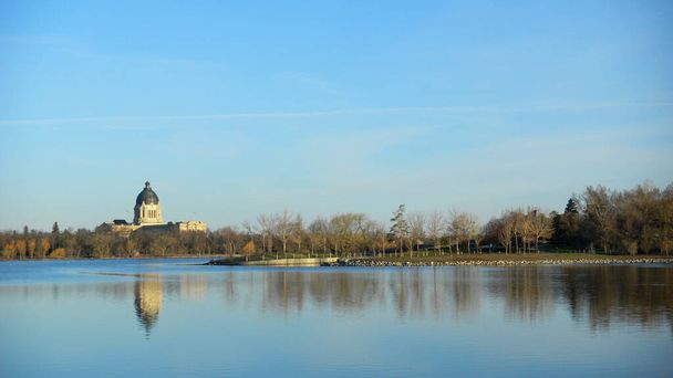 Grand bâtiment en forme de dôme au bord du lac. Réflexion eau. Ciel bleu d'été. Palais législatif, Regina, Saskatchewan, Canada
 - Photo, image