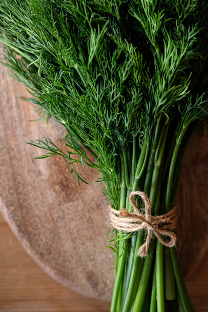 A bunch of dill tied with twine on a wooden background - 写真・画像