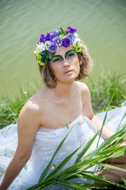 beautiful bride in a wreath of flowers posing outdoors in nature  - Photo, image