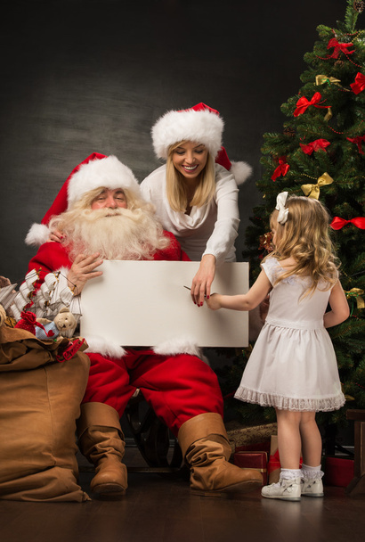 Santa Claus holding white blank sign with family - Fotoğraf, Görsel