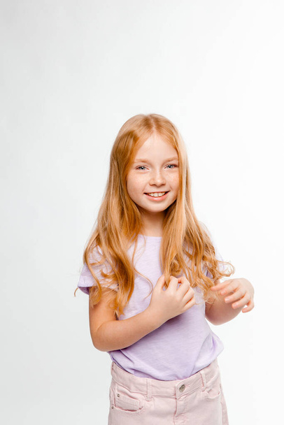 rusovlasá dlouhosrstá dívka v denních šatech (sukně, tričko) si plete vlasy - Fotografie, Obrázek