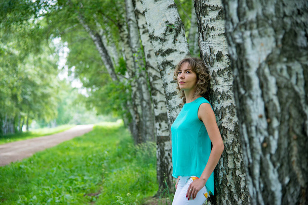 beautiful woman posing outdoors near birch trees - Zdjęcie, obraz