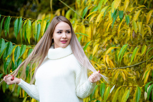 close up portrait of young beautiful woman posing outdoors wearing white sweater  - Fotoğraf, Görsel