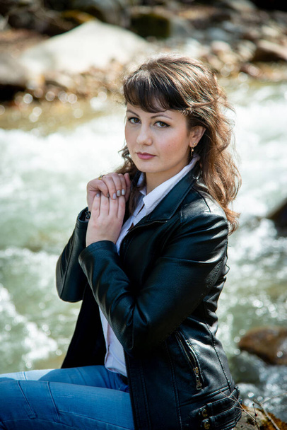 beautiful woman posing outdoors in nature wearing leather jacket and jeans - 写真・画像