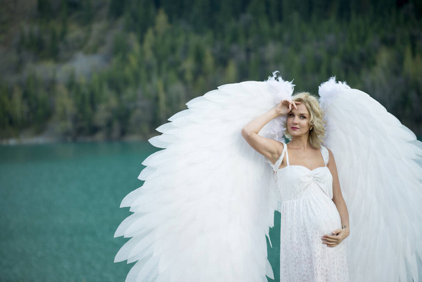 beautiful bride with angel wings posing in nature  - Fotó, kép