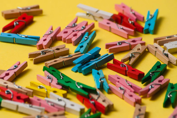 Multicolored decorative wooden clothespins on a yellow background - Photo, Image