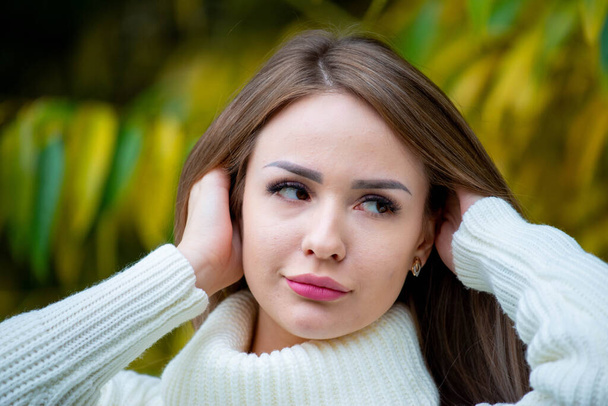 close up portrait of young beautiful woman posing outdoors wearing white sweater  - Photo, Image