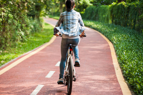 Female cyclist riding mountain bike in park - Foto, Bild