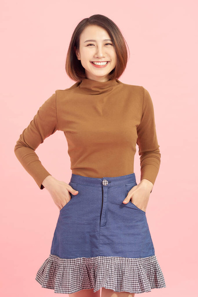 alegre joven asiática mujer de negocios de pie aislado en rosa fondo
. - Foto, Imagen