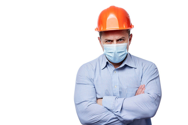 Engineer in face mask and hard hat with arms folded on white background - Fotografie, Obrázek