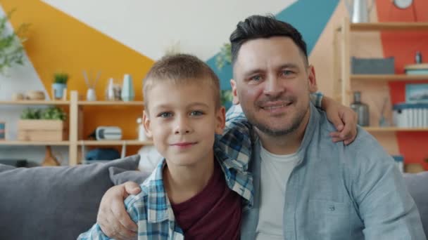 Slow motion of happy family dad and little boy smiling looking at camera in apartment - Záběry, video