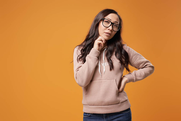 Pensive brunette woman in glasses with long hair isolated in studio - Φωτογραφία, εικόνα