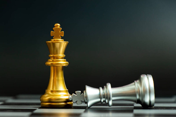 Zlatý král šachy kus vyhrát nad ležící stříbrný král na černém pozadí - Fotografie, Obrázek