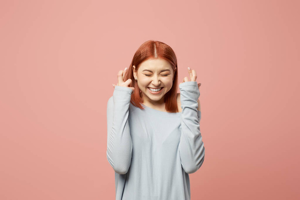 Happy woman with closed eyes in gray sweater standing in studio - Fotoğraf, Görsel