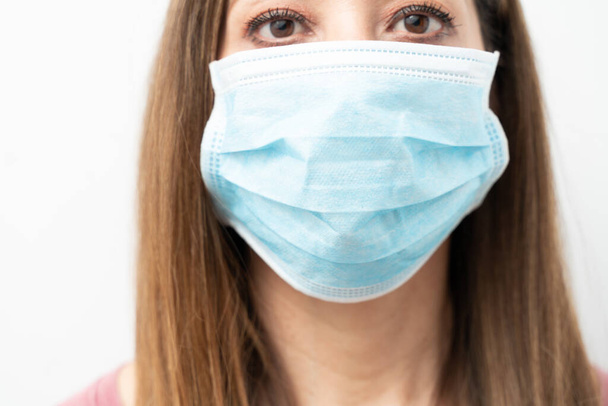 Closeup of a woman with brown hair wearing surgical mask in a studio - 写真・画像