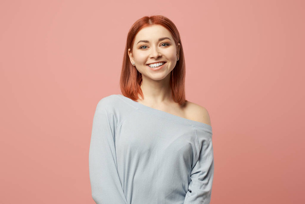 Happy ginger woman in gray sweater standing in studio - 写真・画像