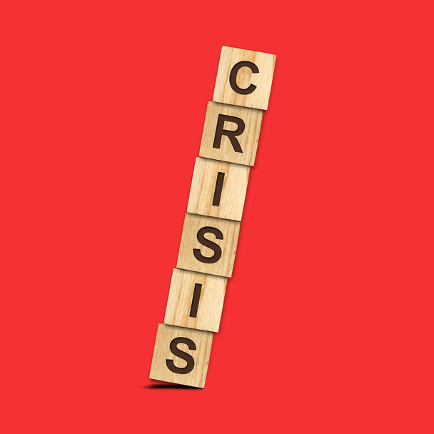 Een crisis. Vallende piramide van houten blokken op een rode achtergrond. Een crisis. Zaken. Financiën. De ineenstorting van de economie. - Foto, afbeelding