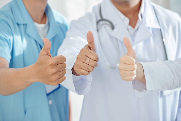 Крупный план изображения врачей и хирургов, показывающих большой палец вверх после выздоровления пациентов
 - Фото, изображение
