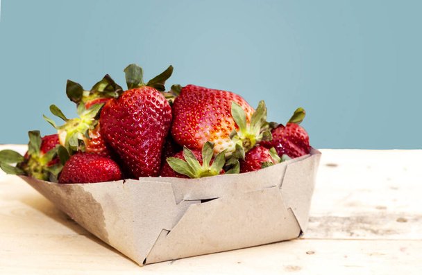 Karton mit frisch gepflückten Erdbeeren auf Holztisch - Foto, Bild