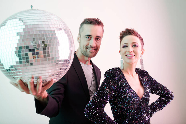 Happy smiling performing duet posing with shiny disco ball - Photo, Image