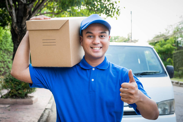 Blue Delivery man holding parcel cardboard box. - Fotografie, Obrázek