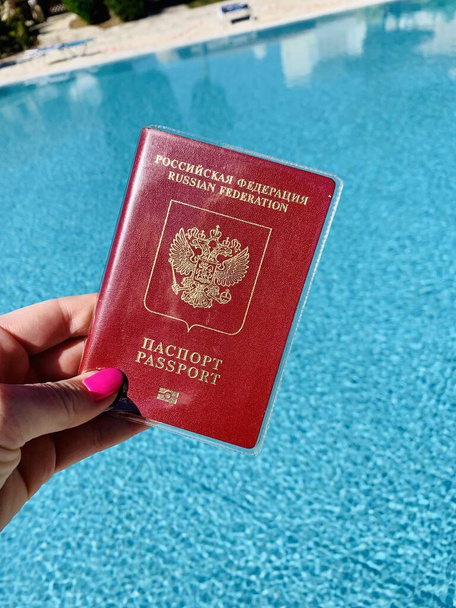Pasaporte ruso internacional en una mano masculina contra un fondo de piscina
 - Foto, imagen