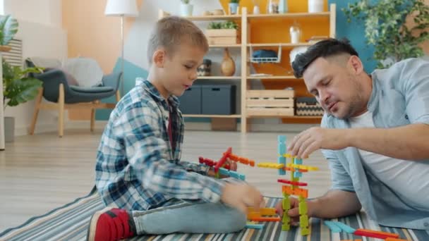 Happy kid playing with joyful dad using construction blocks enjoying funny game - Filmati, video