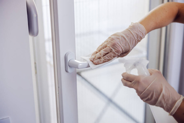 Corona virus prevention, cleaning woman wiping doorknob with antibacterial cleanser for killing coronavirus on touching surfaces. - Photo, Image