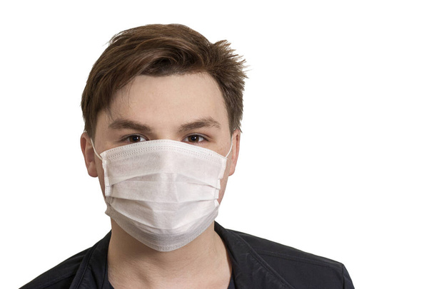 Corona virüsü. Beyaz arka planda maskeli genç bir adam. Virüslere, enfeksiyonlara, egzoz dumanlarına karşı koruma - Fotoğraf, Görsel