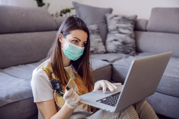 Young woman at home working on laptop, remote office. Online shopping during quarantine and corona preventive measures. Stay at home. - Fotografie, Obrázek