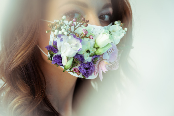 selektywne skupienie atrakcyjnej kobiety w kwiatowej masce na twarzy patrząc na aparat fotograficzny na białym - Zdjęcie, obraz