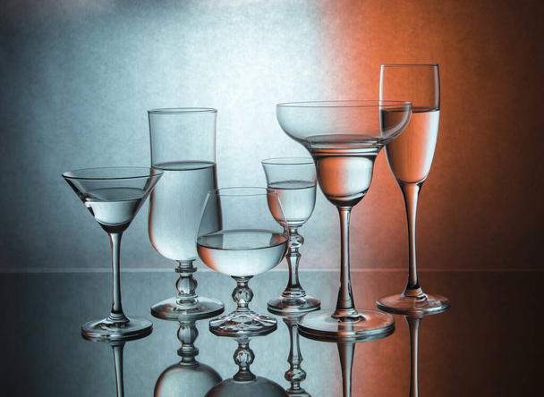 Six glass goblets on color gradient background - Foto, imagen