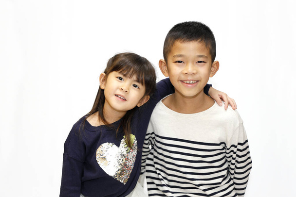 Japanese brother and sister putting arms around each other's sholders (10 years old boy and 5 years old girl) - Photo, Image