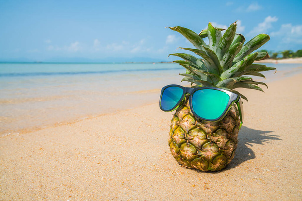 Pineapple with sunglasses on tropical beach background. Summer concept - Foto, immagini