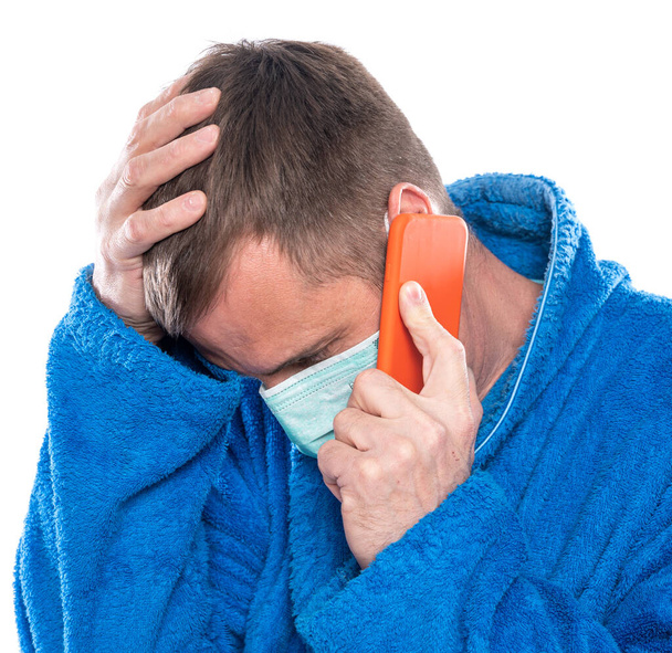 Medicine and healthcare concept. Sick man in mask and home bathrobe talking on mobile phone over white background - Fotografie, Obrázek