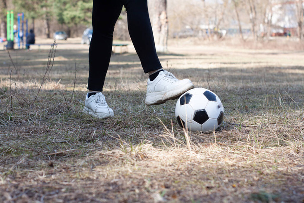 a girl in white sneakers plays with a soccer ball - Фото, изображение