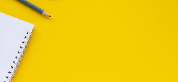 Notebook, pencil on a yellow background. Top view space for copy or text. - Foto, afbeelding