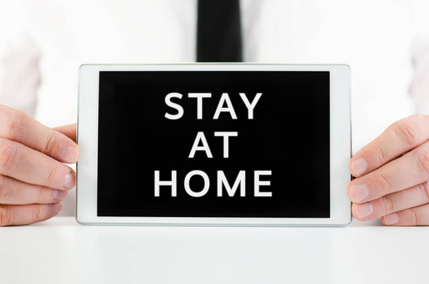 Biznesmen trzymając inteligentny tablet ze znakiem Zostań w domu na ekranie, zachęcając ludzi do pozostania w domu - Zdjęcie, obraz
