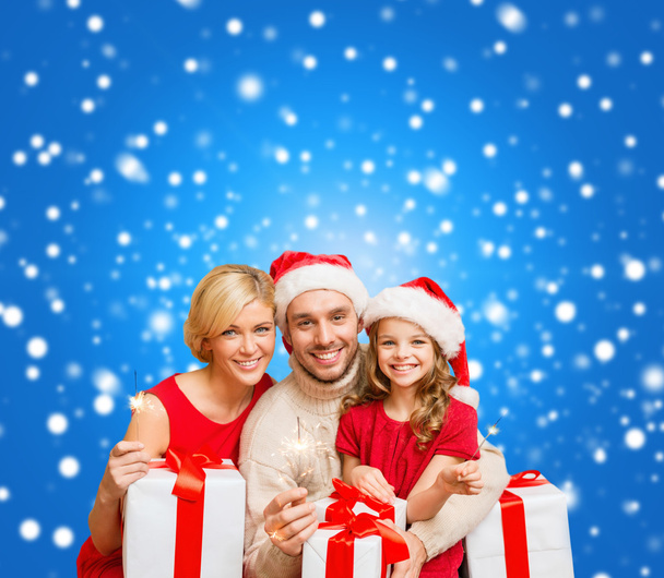 Smiling family holding gift boxes and sparkles - Photo, Image
